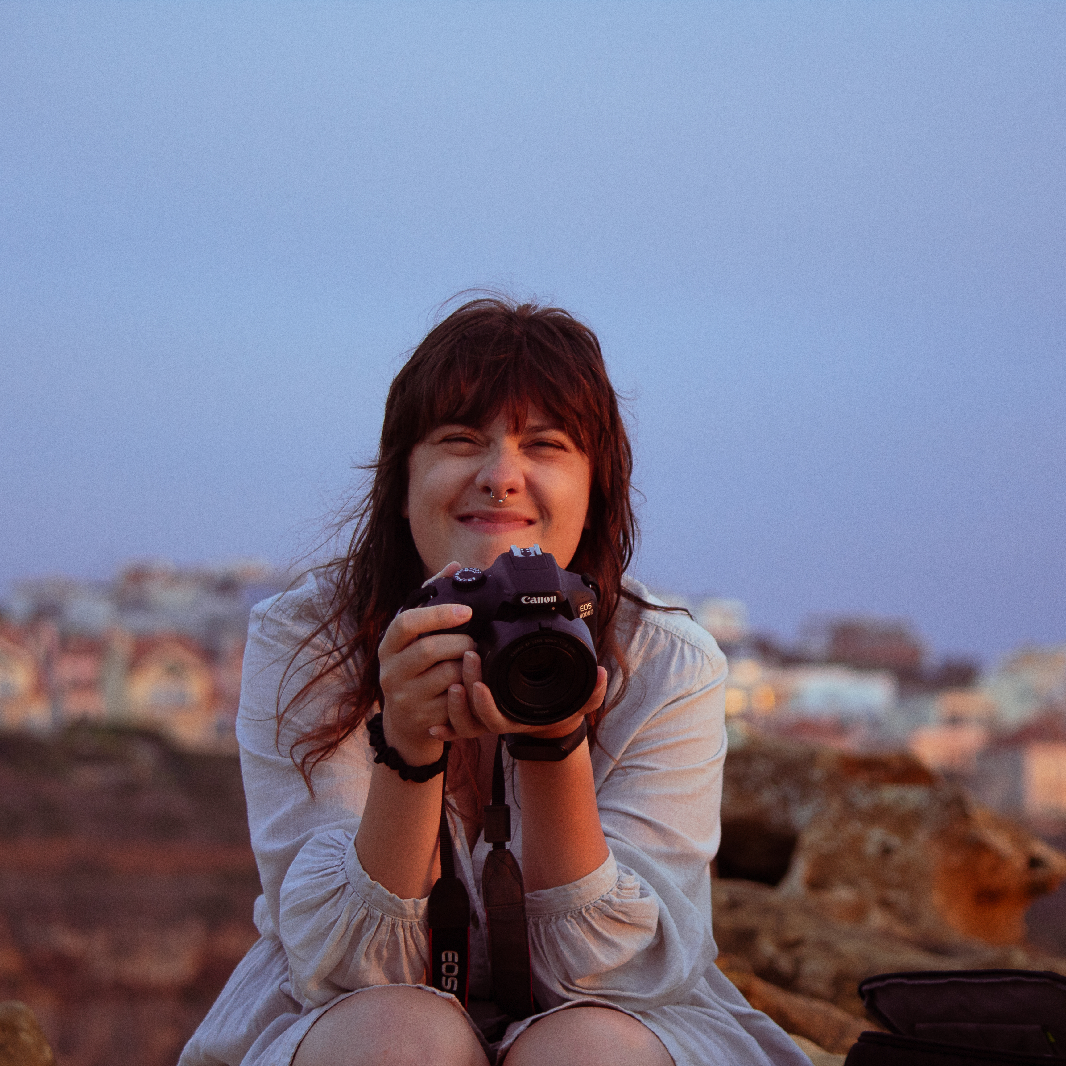 Foto che ritrae Matilda Masciulli aka mmWebdesigner, con una macchina fotografica in mano, che sorride mentre si trova seduta in all'esterno